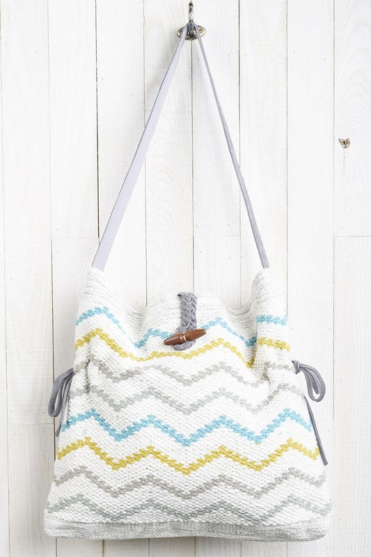Carpet bag with suede side tie pulls and suede handle.